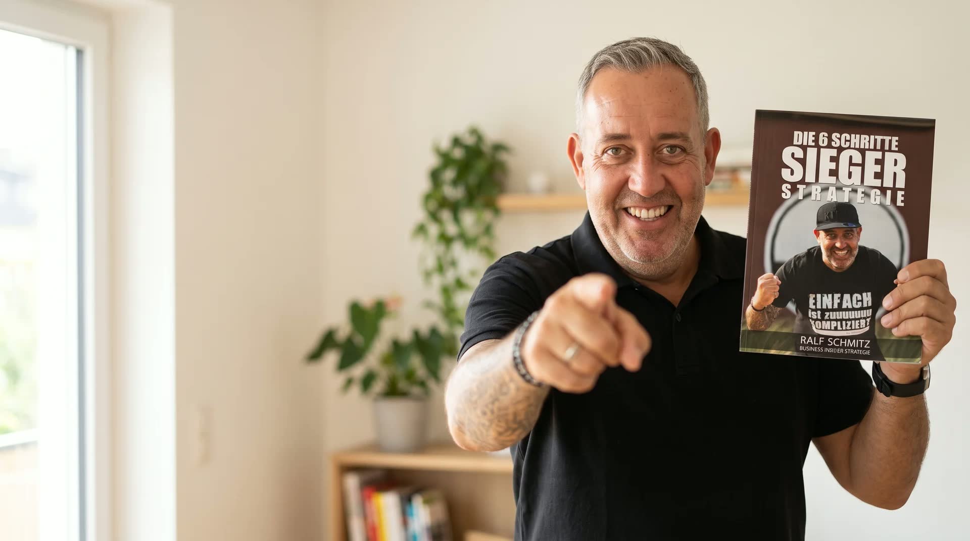 Ralf Schmitz hält das PDF „Die 6 Schritte Sieger Strategie“ hoch und zeigt nach vorn